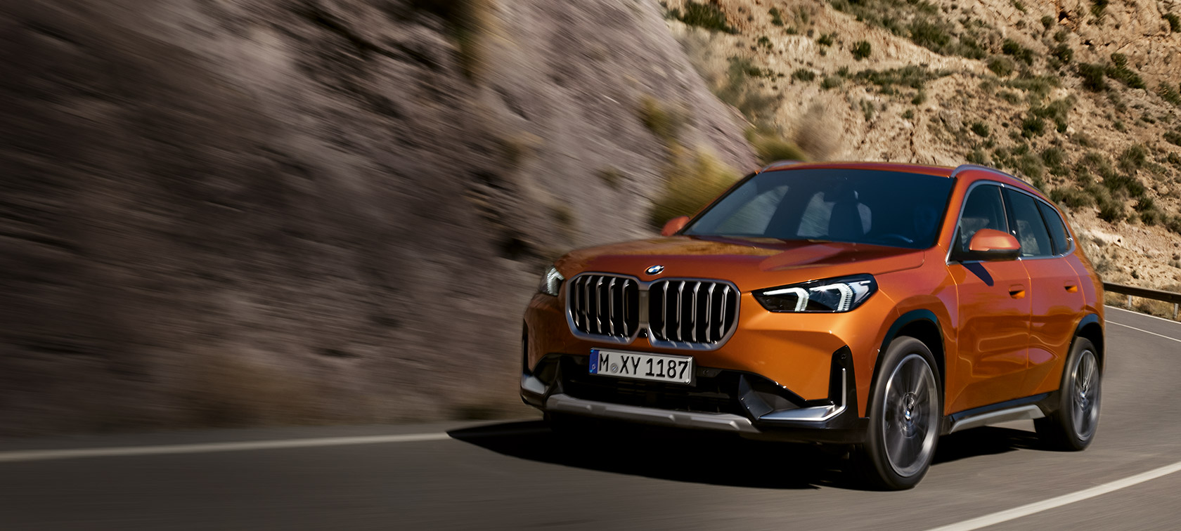 BMW X1 U11 xLine metalíza Utah Orange predobočný pohľad jazdný na vidieckej ceste